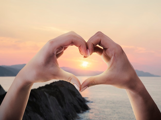 Free photo heart-shaped hands on a sunset