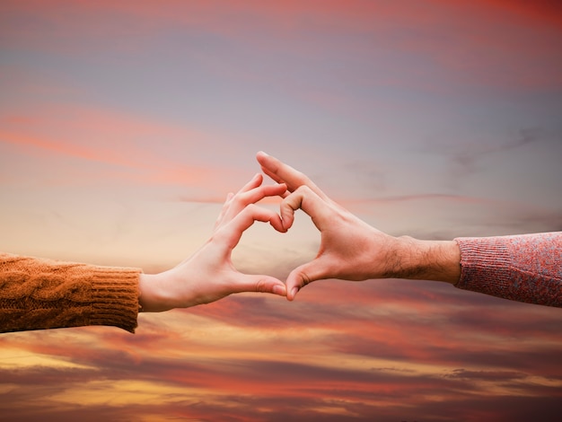 Free photo heart-shaped hands on a sunset