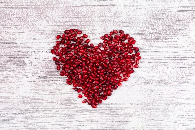 Free photo heart shaped pomegranate top view on white d table