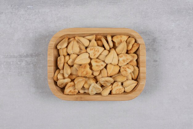 Heart shaped salty crackers on wooden plate.