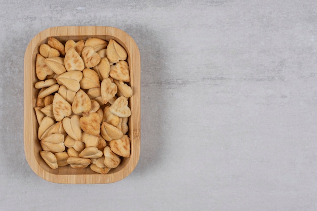 Heart shaped salty crackers on wooden plate.