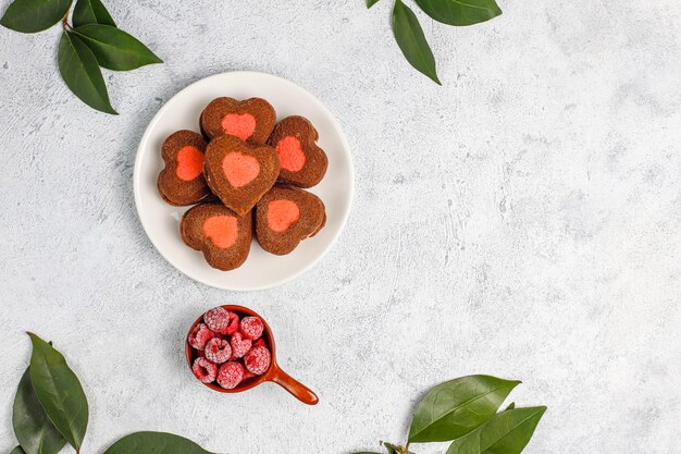 Heart shaped valentine cookies with frozen raspberries on light background