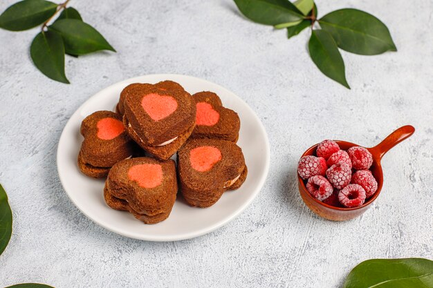 Foto gratuita biscotti di san valentino a forma di cuore con lamponi congelati su sfondo chiaro