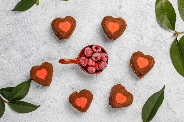 Heart shaped valentine cookies with frozen raspberries on light