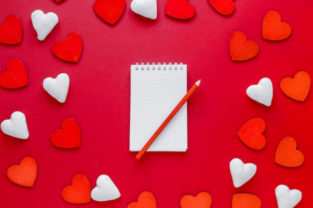 Free photo hearts around notebook with pencil