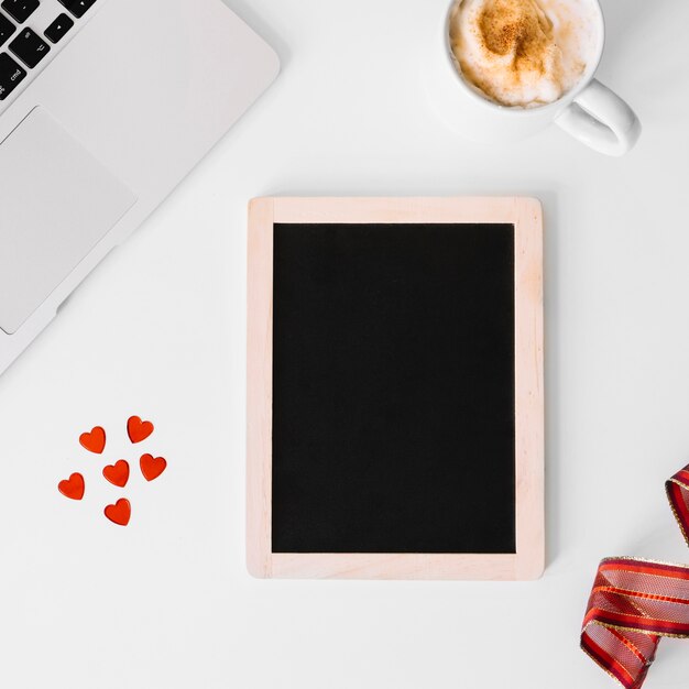 Hearts and blackboard near laptop and coffee