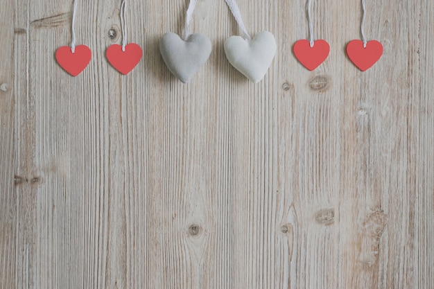Free photo hearts hanging from ropes on a wooden surface