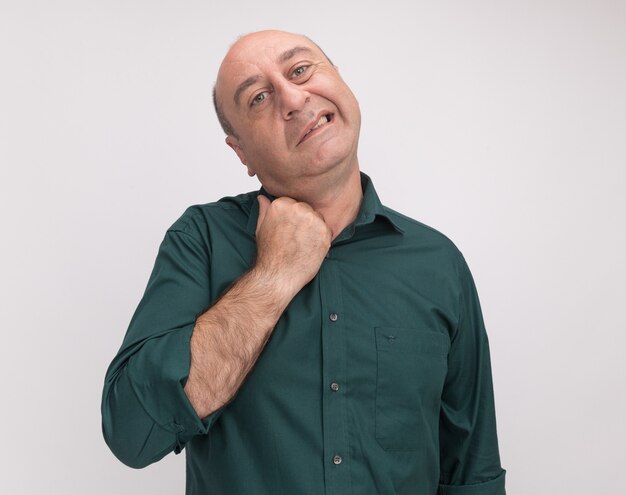 Heated middle-aged man wearing green t-shirt holding collar isolated on white wall