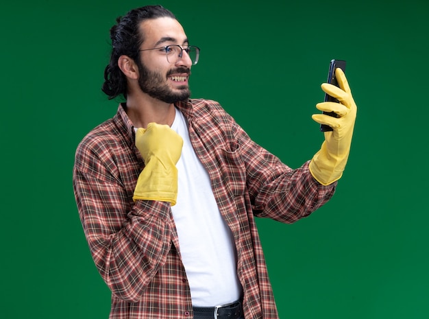 Il giovane e bel ragazzo delle pulizie riscaldato che indossa maglietta e guanti prende un collare afferrato selfie isolato sul muro verde