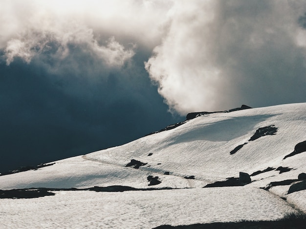 Heavy clouds hang over the mountains covered with snow