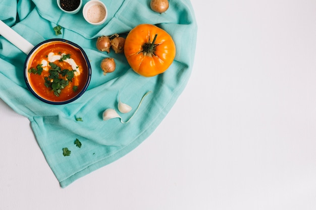 Heirloom tomato recipe in saucepan on blue napkin against white background