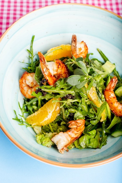 Herb salad topped with orange and fried shrimps