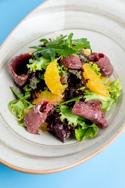 Herb salad topped with orange and ham slices