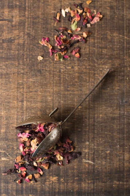 Herbal aroma tea dry petals with strainer on wooden textured backdrop