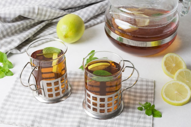 Herbal lemon and mint tea on tablecloth against white background