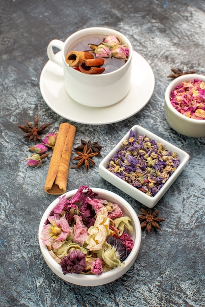 Herbal tea with bowls of dry flower on grey ground