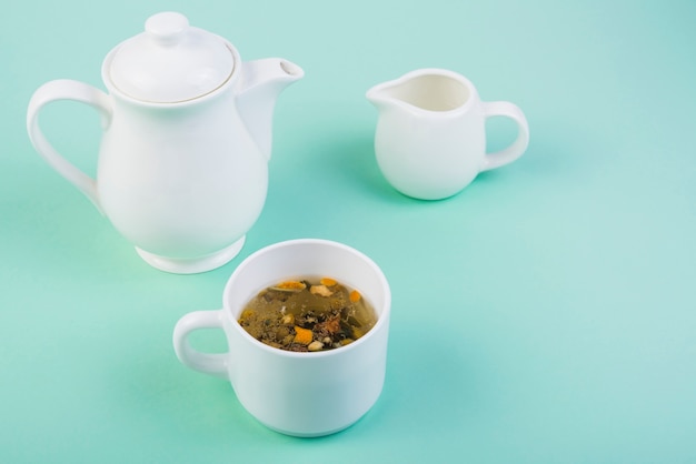 Herbal tea with crockery on turquoise background