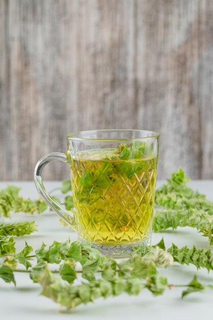 Herbal tea with leaves in a glass cup on white and grungy,