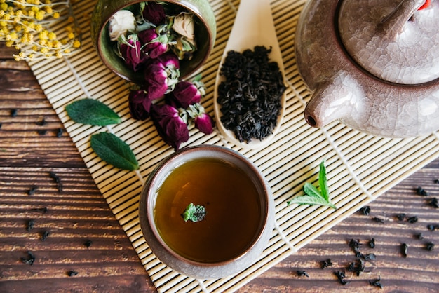 Herbal teacup with dried rose flower and dry leaves on placemat