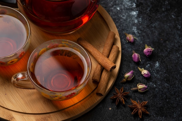 Herbal winter tea in the cups with spices on a wooden platter, top view. 