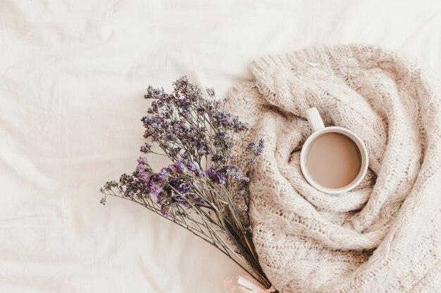 Herbs near hot drink in plaid on bedsheet