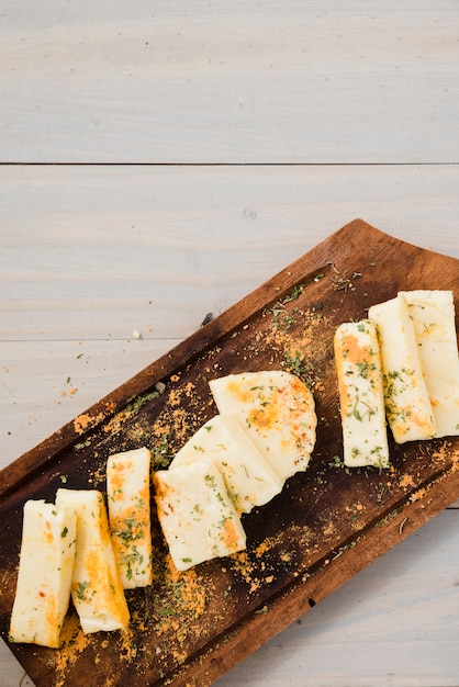 Foto gratuita erbe e spezie su fette di formaggio sopra il tavolo di legno