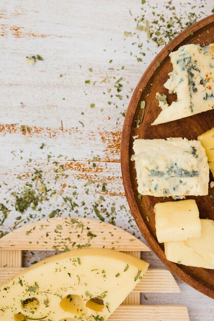 Herbs with cheese on wooden coaster over the plank