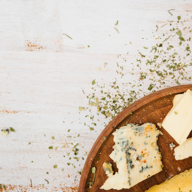 Foto gratuita erbe con formaggio sul vassoio di legno sopra la scrivania bianca