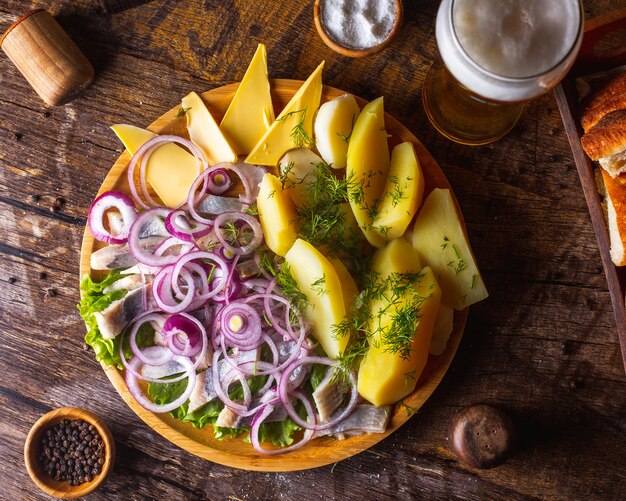 Herring with onion potatoes, butter and greens served with beer 1