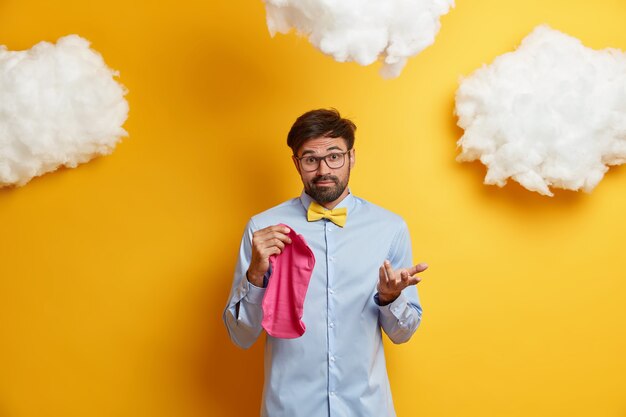 Hesitant unshaven man doesnt know which clothes for newborn to buy has no experience of fatherhood dressed formally 