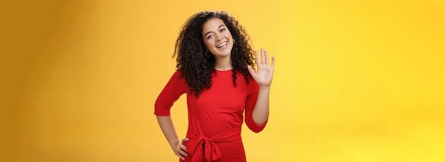 Free photo hey my name is friendlylooking selfassured carefree cute s woman with curly hair waving with raised