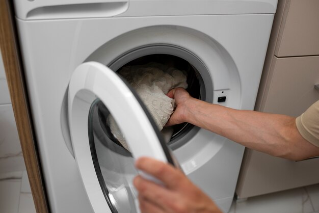 Взрослый загружает стиральную машину под большим углом