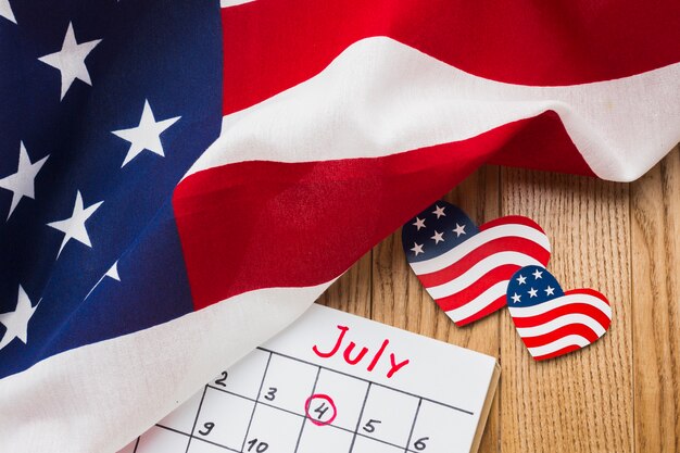 High angle of american flags and calendar on wooden surface