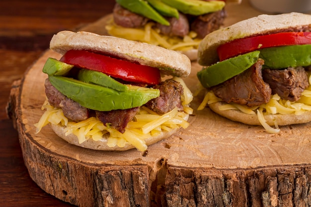 Foto gratuita alto angolo di arepas con avocado e carne su tavola di legno