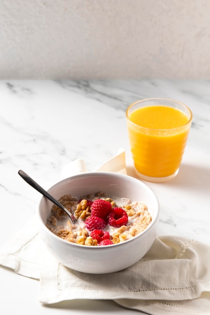 High angle arrangement of healthy bowl cereals with orange juice