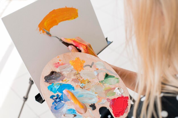 High angle of artist painting while holding paint palette