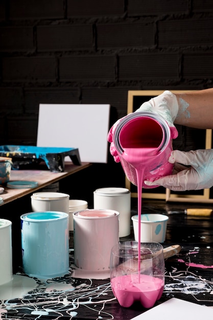 High angle of artist pouring pink paint from can