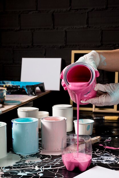 High angle of artist pouring pink paint from can