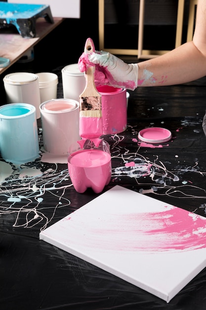 Free photo high angle of artist using pink paint on canvas