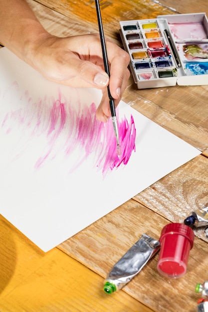 High angle of artist with paint brush painting in studio