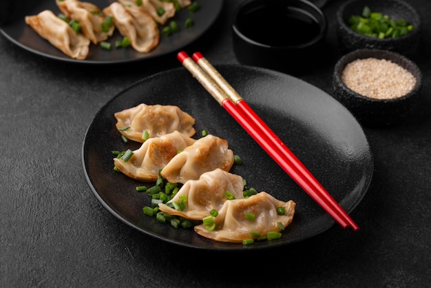 High angle of asian dumplings dish with herbs and chopsticks