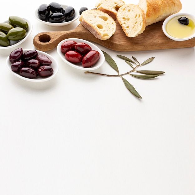 Free photo high angle assortment of olives bread slices and olive oil