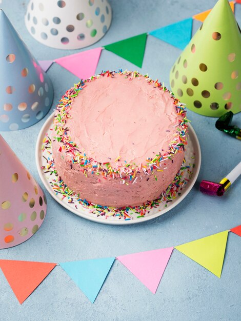 High angle assortment with party hats and pink cake