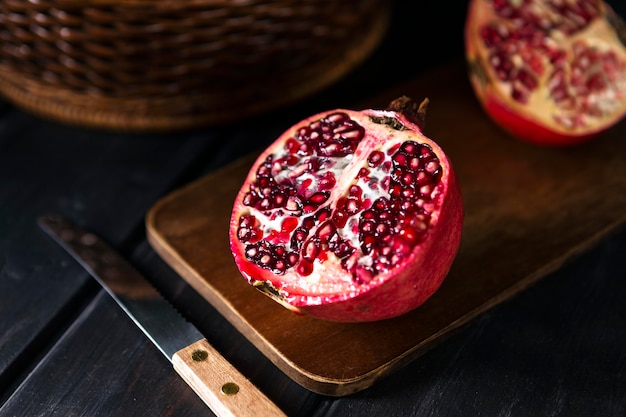 High angle of autumn pomegranate halves with knife and chopping board