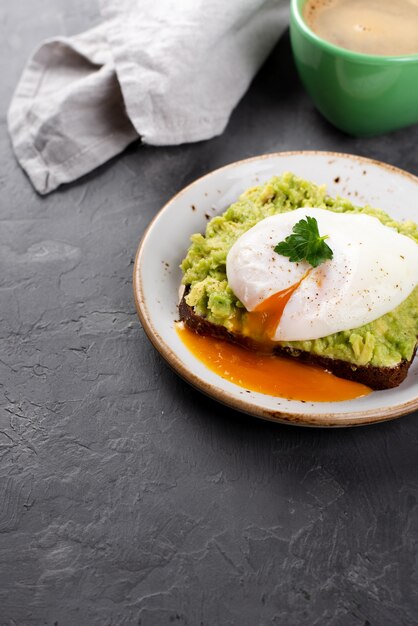 High angle of avocado toast with poached egg and cup of coffee