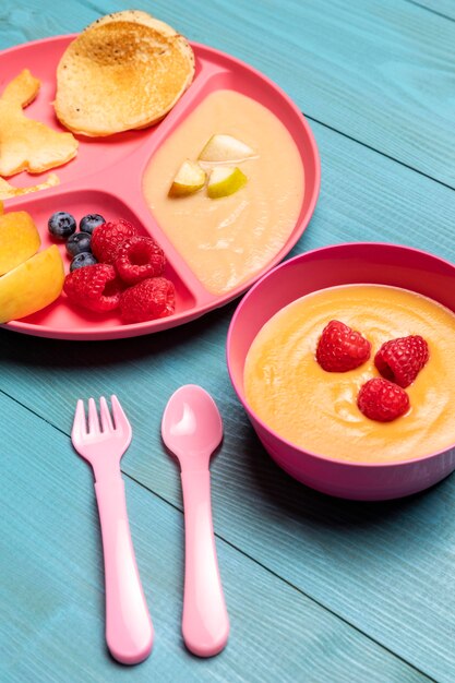 High angle of baby food in bowl with assortment of fruits