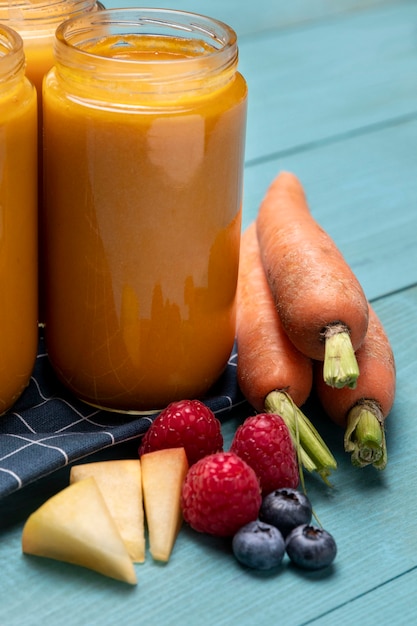 High angle of baby food in jars with fruits and carrots