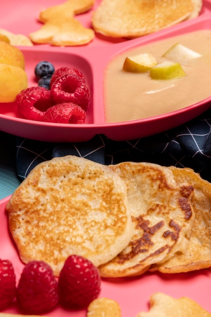 High angle of baby food with raspberries and pancakes