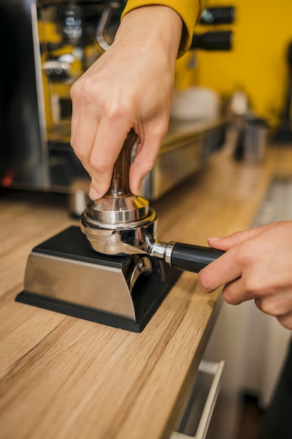 High angle of barista packing coffee in cup for machine