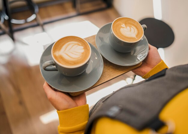 High angle of barista serving cups of coffee